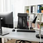 Bureau professionnel épuré avec moniteur, chaise ergonomique et lampe de bureau, illustrant les meilleurs accessoires tech pour un espace de travail productif