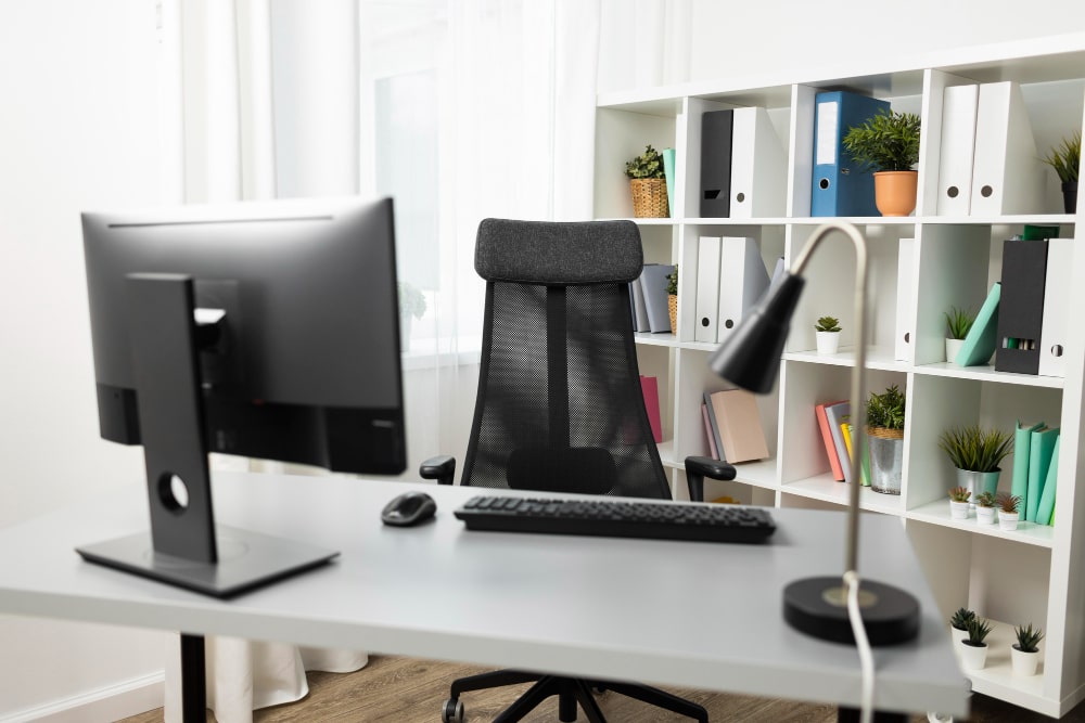 Bureau professionnel épuré avec moniteur, chaise ergonomique et lampe de bureau, illustrant les meilleurs accessoires tech pour un espace de travail productif